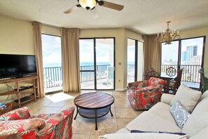 A spacious living room with a flat-screen TV, a round coffee table, and two sofas with floral upholstery. - Phoenix East 1201 (Orange Beach)