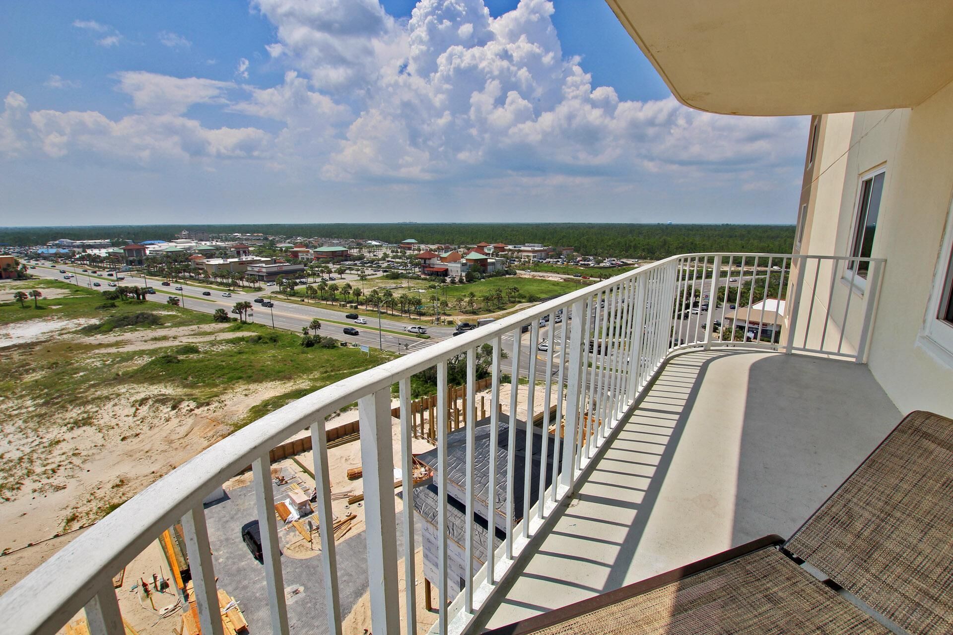A balcony with a view of a town, construction site, and a road with vehicles.