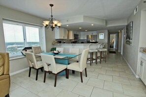 A modern kitchen with white cabinets, a central island, and a dining area with a glass table and chairs.