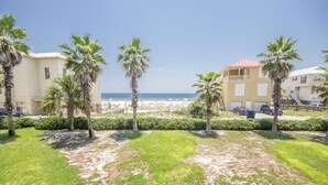 A beachfront property with palm trees, a sandy beach, and a clear view of the ocean.