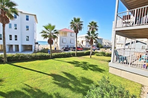 Un quartier résidentiel avec une pelouse bien entretenue, des palmiers et une vue sur la mer.