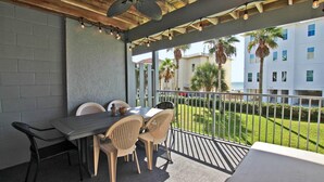 A covered outdoor dining area with a table and chairs, a ceiling fan, and string lights.