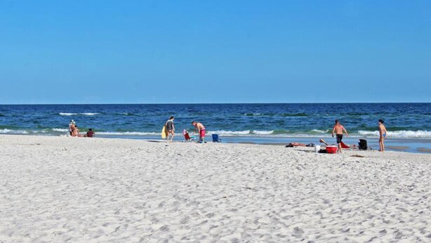 A sandy beach with people and beach equipment. - Serendipity Sands (Gulf Shores)
