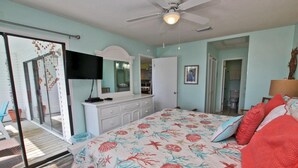 A bedroom with a large bed, a ceiling fan, a sliding glass door leading to a balcony, and a white dresser. - Palmetto 306 (Orange Beach)