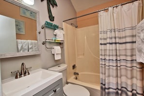 A bathroom with a sink, toilet, and bathtub. There is a towel rack with towels and toiletries.