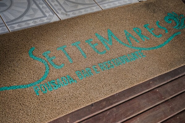Una alfombra de entrada con el texto "SETTEMARES" y "Pousadas, Bar & Restaurante", indicando un hotel o restaurante.