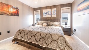 Quarto moderno com uma cama grande, uma mesinha de cabeceira e uma TV na parede.