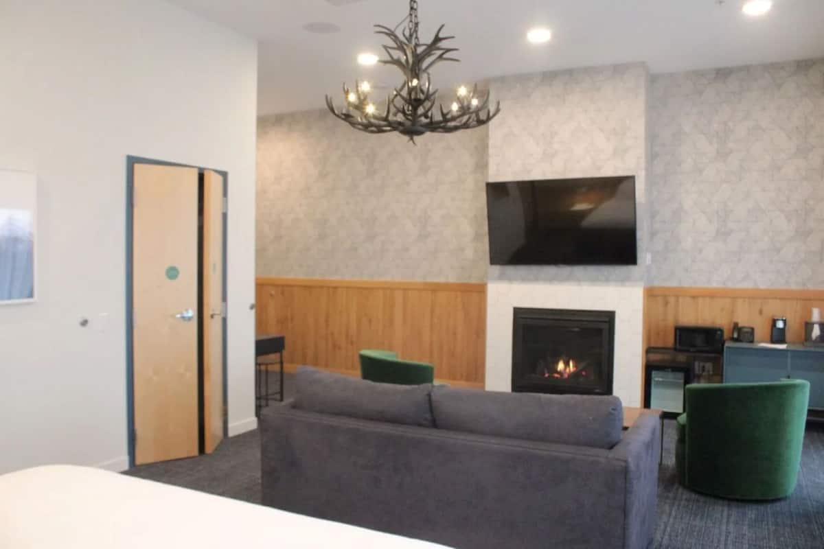 A modern living room with a fireplace, a sofa, a television, and a chandelier.