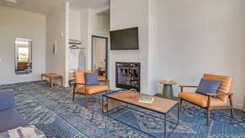 Una sala de estar con chimenea, dos sillones de cuero, una mesa de centro y una alfombra estampada.