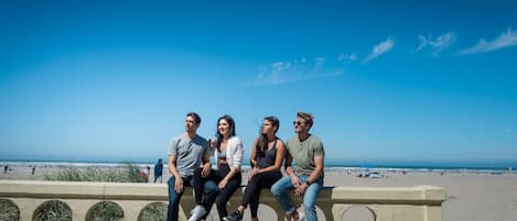 A group of people sitting on a concrete bench overlooking a beach.