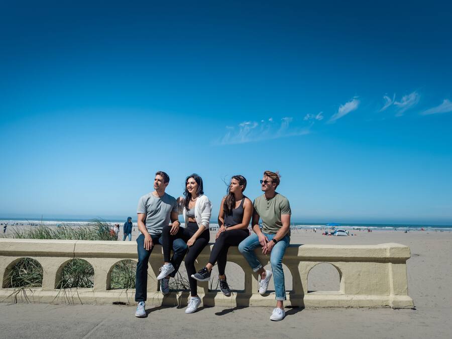 Eine Gruppe von Personen sitzt auf einer Betonbank mit Blick auf einen Strand.