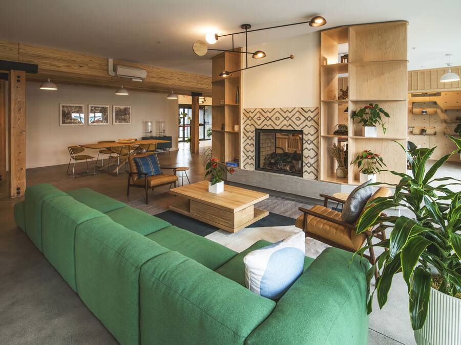 Una sala de estar moderna con un sofá verde, una mesa de centro de madera y una chimenea.