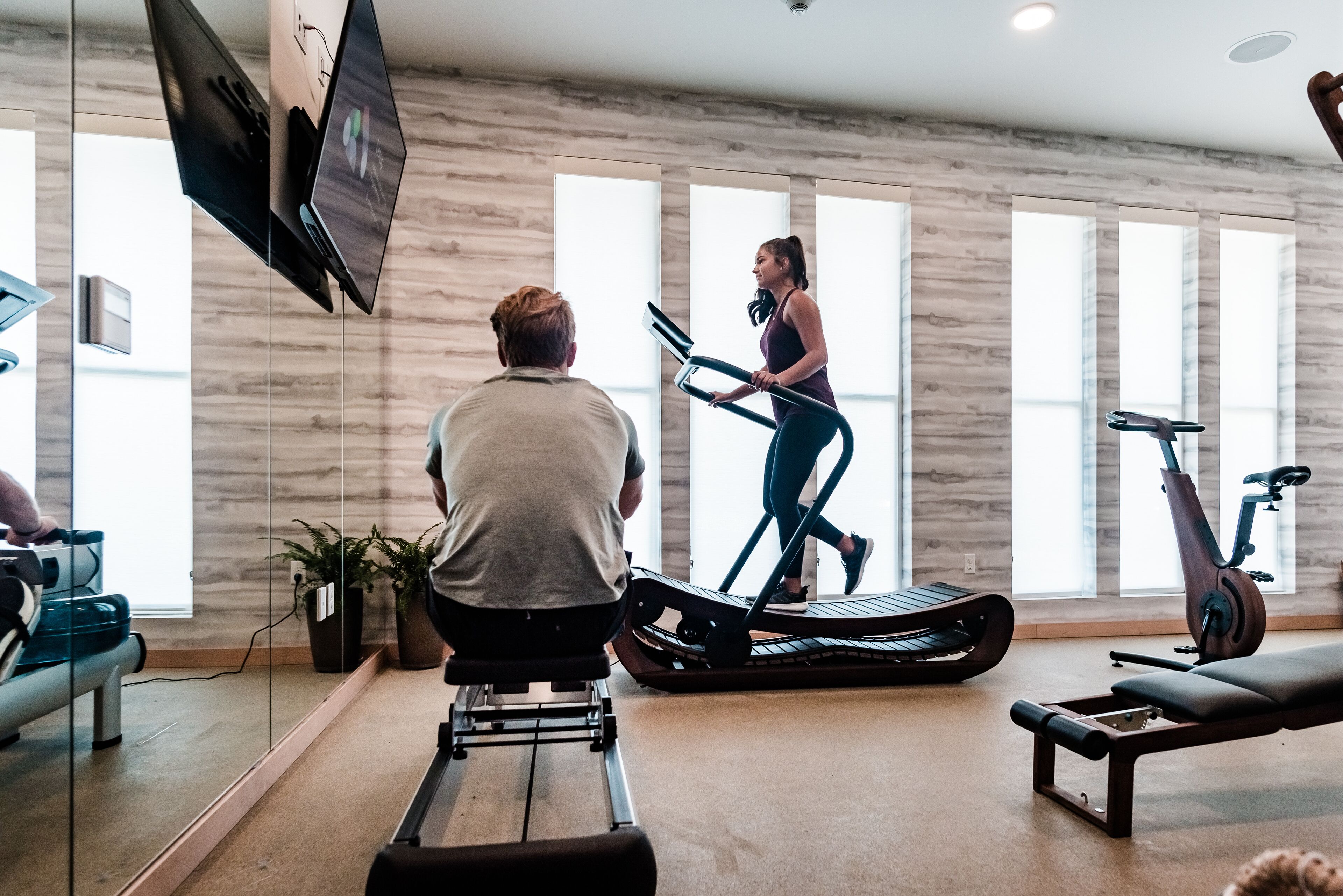 Un gimnasio moderno con bicicletas estáticas, una cinta de correr y una máquina de remo.