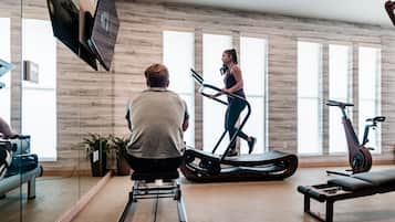 Un gimnasio moderno con bicicletas estáticas, una cinta de correr y una máquina de remo.