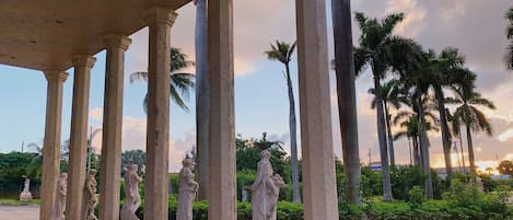 Une série de colonnes ornées de statues, disposées dans un jardin.