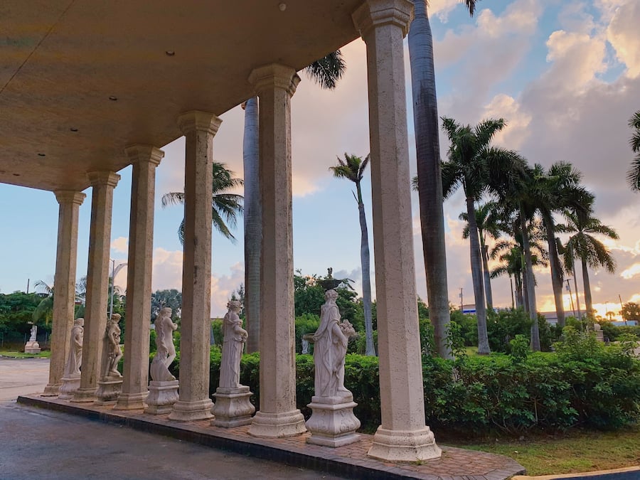 A series of columns with statues in a garden setting.