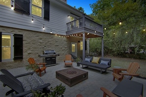 A patio with outdoor furniture, a grill, and string lights.