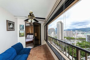 Uma varanda com vista para a cidade, um ventilador de teto e uma cama com vista.