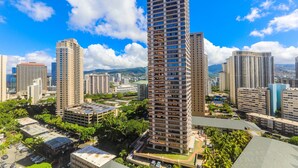A high-rise building with a modern architectural design, surrounded by other high-rise buildings and greenery. - Discovery Bay, Conveniently Located In Waikiki, near Ala Moana Shopping Center & the beach! (Honolulu)