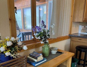 A wooden table with a vase of flowers, a book, and a small bowl.
