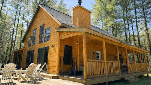 A wooden cabin with a porch, outdoor seating, and a chimney. - Camp Pinemere - Private Northwoods Retreat (Minocqua)