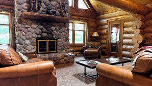 A log cabin interior with a stone fireplace, leather sofas, and a wooden ceiling. - Katherine Lake Lodge (Hazelhurst)