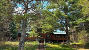 A wooden cabin with a green roof, surrounded by trees and a pathway leading to it. - Katherine Lake Lodge (Hazelhurst)