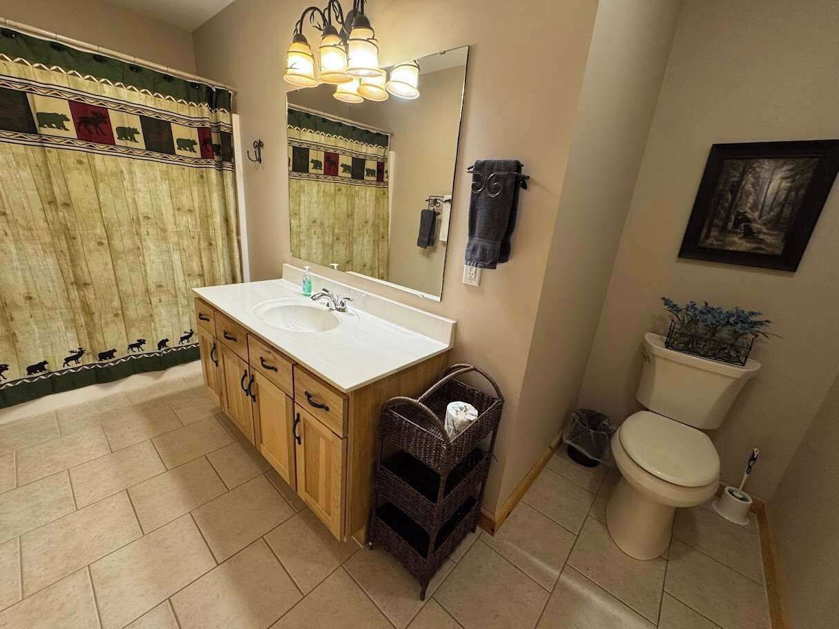 Een badkamer met een houten wastafel, een wastafel, een spiegel en een toilet.