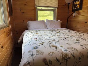 A wooden room with a bed, a window, and a lamp. - Minocqua Shores Cabin #2 (Minocqua)