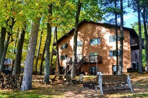 A cabin with a wooden exterior, multiple windows, and a balcony. - Minocqua Shores Condo #7 (Minocqua)