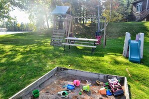 Un parc infantil amb tobogan, cadira de balanceig i taula de pícnic.