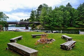 Un parque junto al lago con mesas de picnic, un pequeño puente y barcos amarrados cerca del agua.