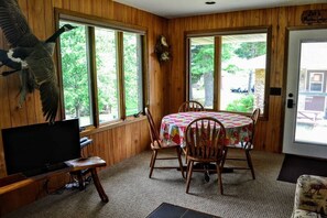 A wooden-paneled room with a table and chairs, a television, and a mounted bird.