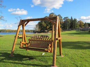 Un parc amb un conjunt de balanços de fusta i un estany al fons.