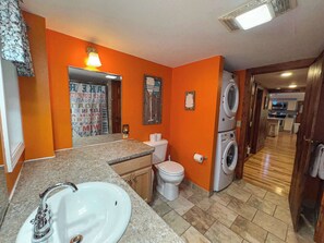 Un baño pequeño con lavamanos, inodoro y lavadoras apiladas.