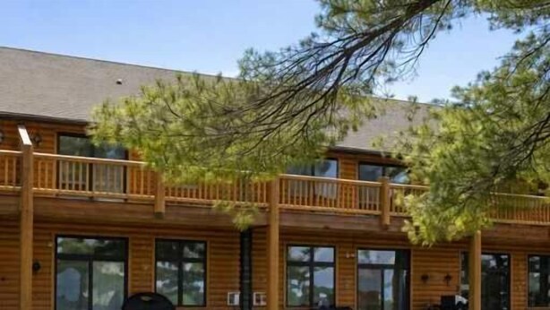 A log cabin with a balcony, large windows, and a picnic area with benches. - Minocqua Lake Condo B10 (Minocqua)