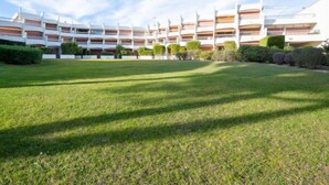 A modern hotel with a central courtyard, multiple balconies, and a well-maintained lawn.