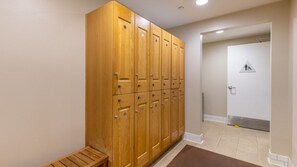 Un couloir avec des casiers en bois, un banc et une porte accessible aux personnes en fauteuil roulant.