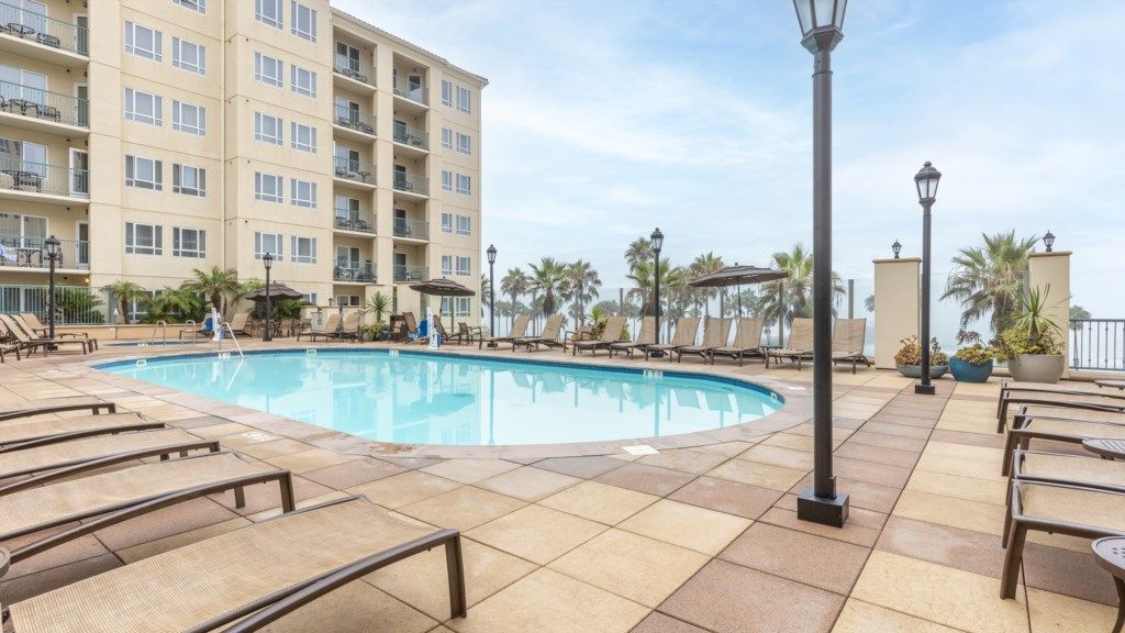 A pool area with lounge chairs and a building in the background.