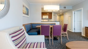 Habitación de hotel con zona de estar que incluye un sofá, un banco y una mesa de comedor con sillas.