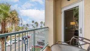A balcony with a view of palm trees and a street.