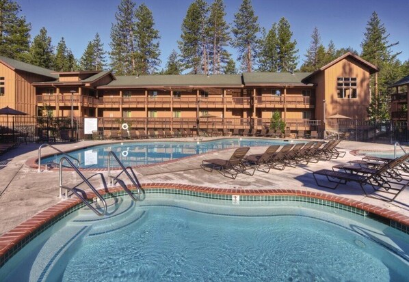 A pool area with lounge chairs and a building with multiple balconies in the background.