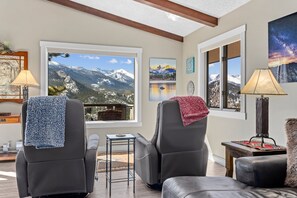 A living room with two leather recliners, a small side table, and a view of mountains through large windows. - Destiny Family Vacation Home at Windcliff by RedAwning (Estes Park)
