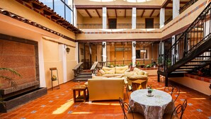 A spacious indoor area with a high ceiling, a staircase, and a seating area with sofas and a table. - Hotel La Casa de Don Tito, Jocotitlán (Jocotitlán)