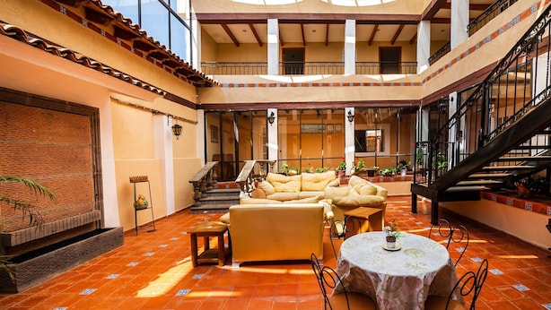 A spacious indoor area with a high ceiling, a staircase, and a seating area with sofas and a table. - Hotel La Casa de Don Tito, Jocotitlán (Jocotitlán)
