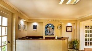 A reception area with a reception desk, a clock, framed certificates, and a stained glass window. - Hotel La Casa de Don Tito, Jocotitlán (Jocotitlán)