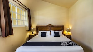 A neatly made bed with a wooden headboard, two bedside tables with lamps, and a window with curtains. - Hotel La Casa de Don Tito, Jocotitlán (Jocotitlán)