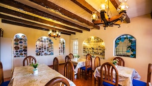 A dining area with wooden tables and chairs, a chandelier, and wall decorations including plates and a mirror. - Hotel La Casa de Don Tito, Jocotitlán (Jocotitlán)