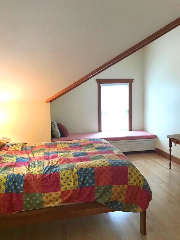 A bedroom with a colorful quilt, a window seat, and a wooden ceiling. - Shore front home in a charming summer community (Sorrento)