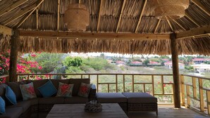 A covered outdoor seating area with a thatched roof, cushioned sofas, and wicker lamps. - Magnificent Villa near Beach in Upscale District of Vista Royal, Jan Thiel (Jan Thiel)